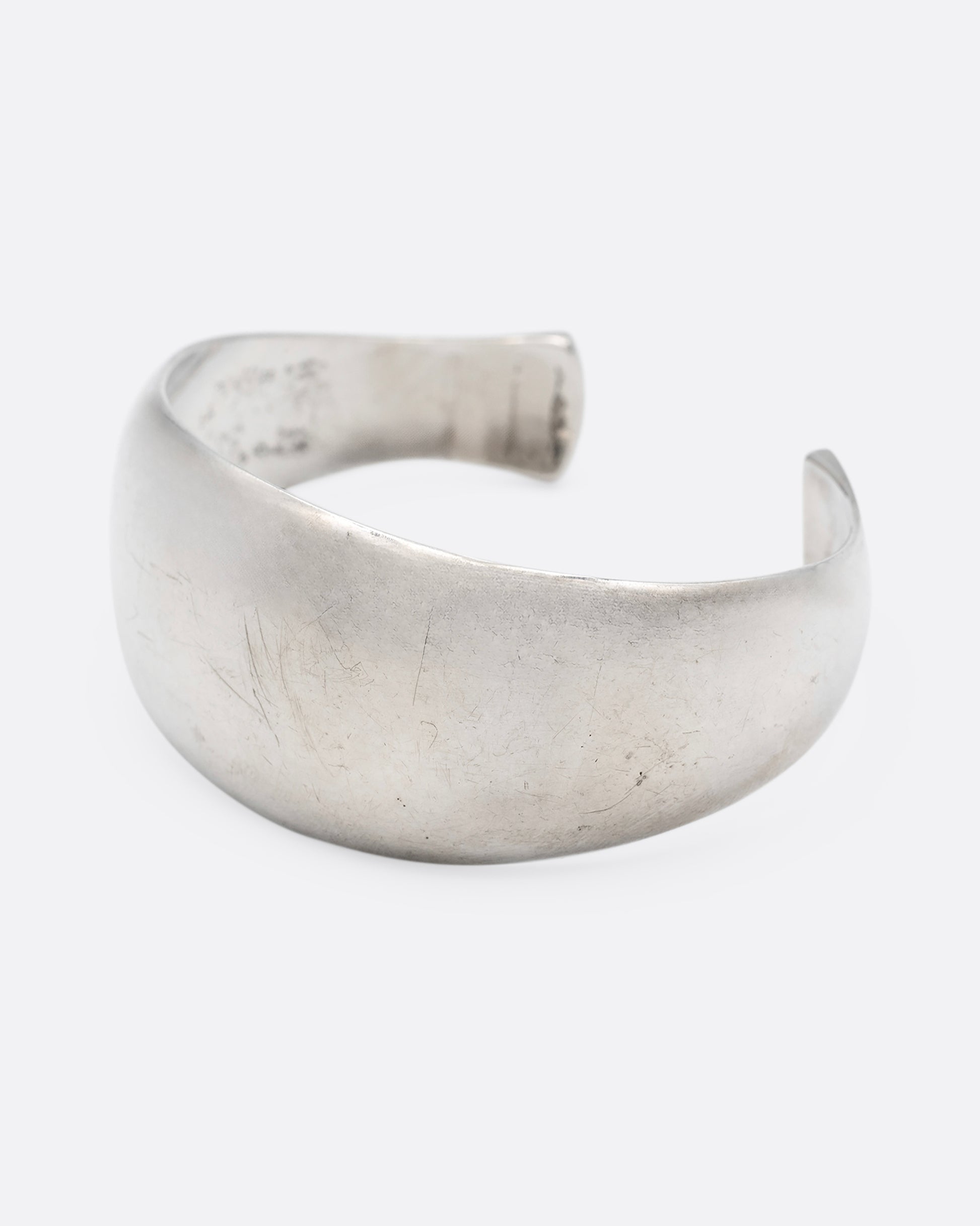 A silver cuff bracelet with smooth edges, shown from the side.