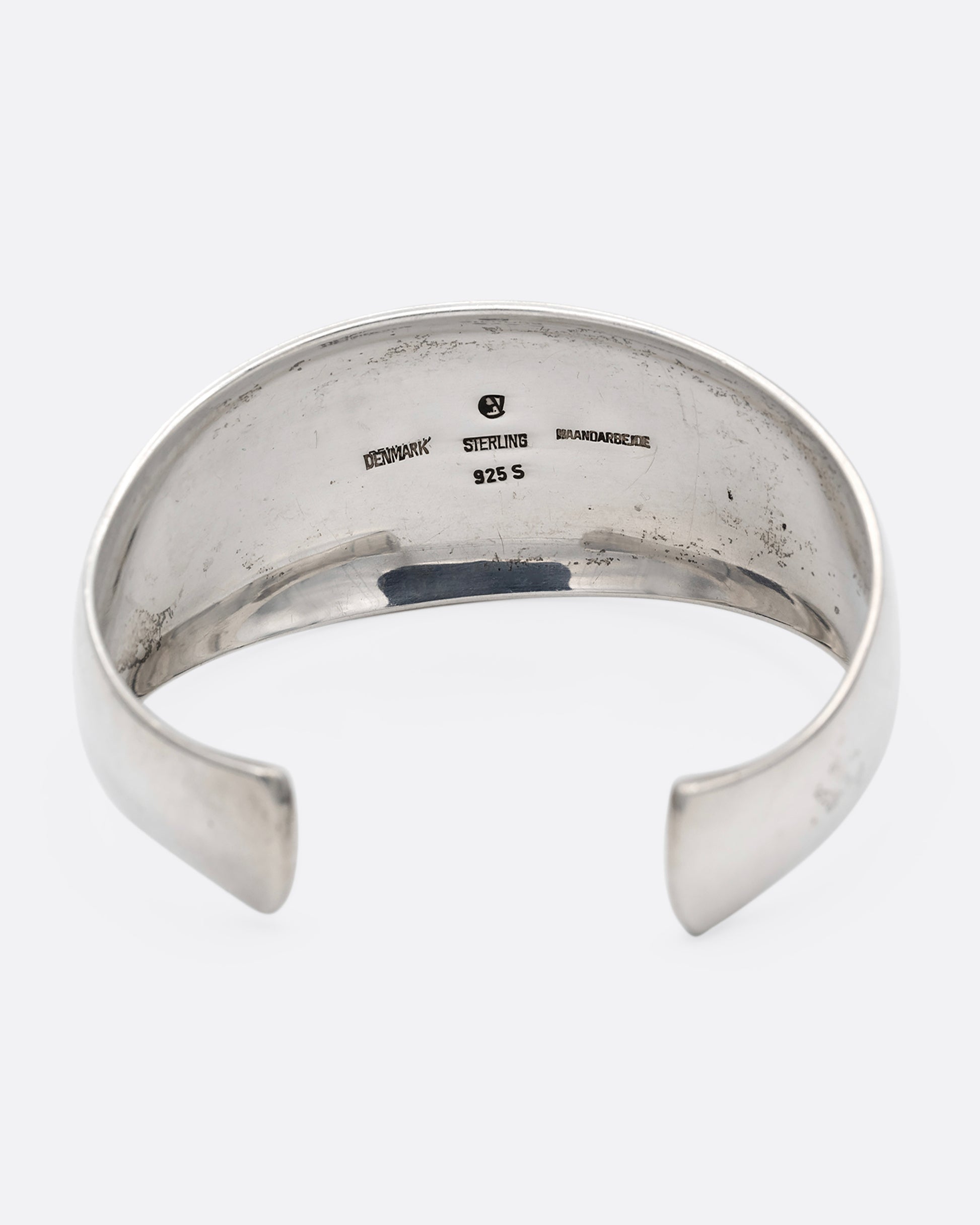 A silver cuff bracelet with smooth edges, shown from the back.