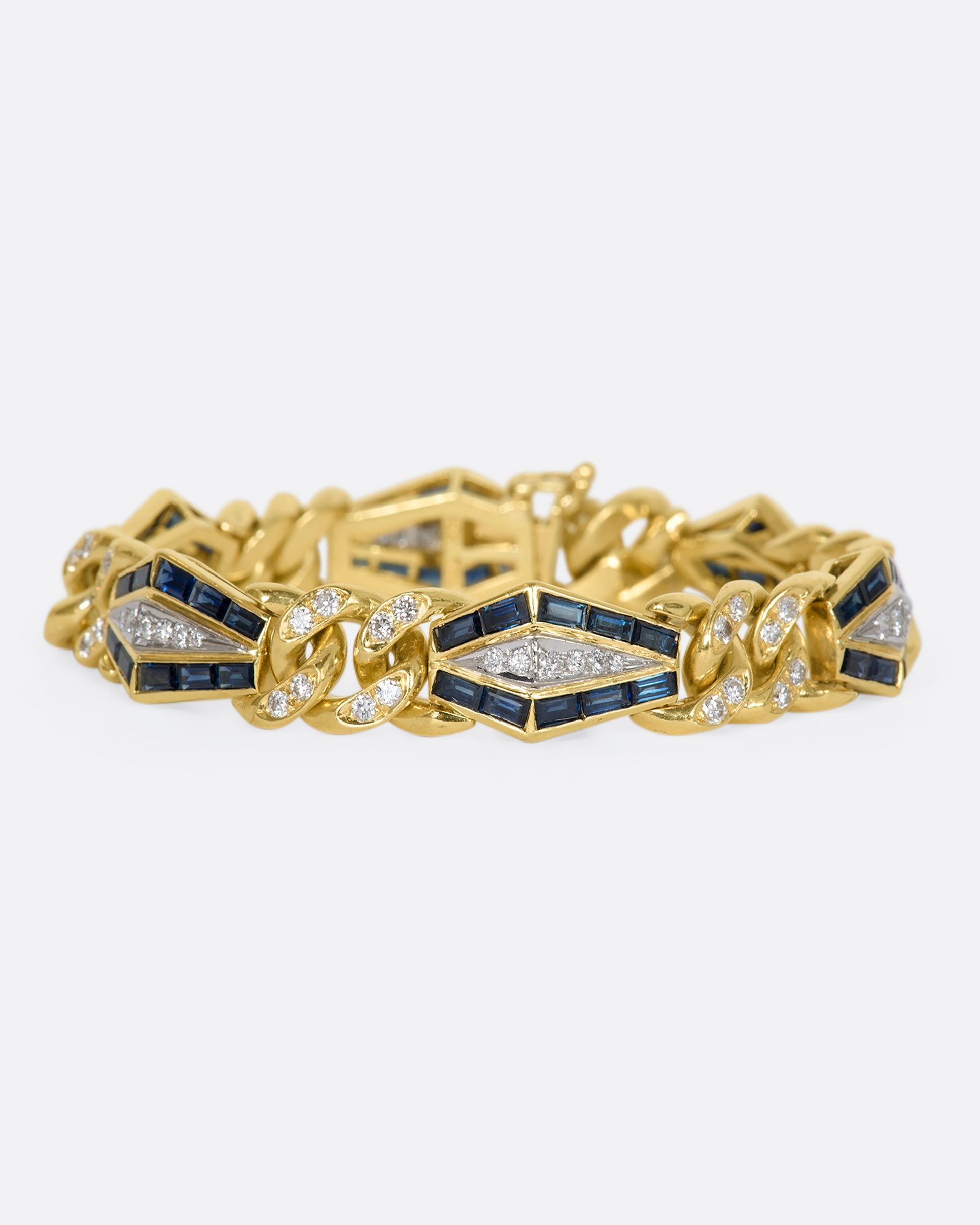 Yellow gold curb chain bracelet with sapphire baguette stations and diamonds throughout. View from the front.