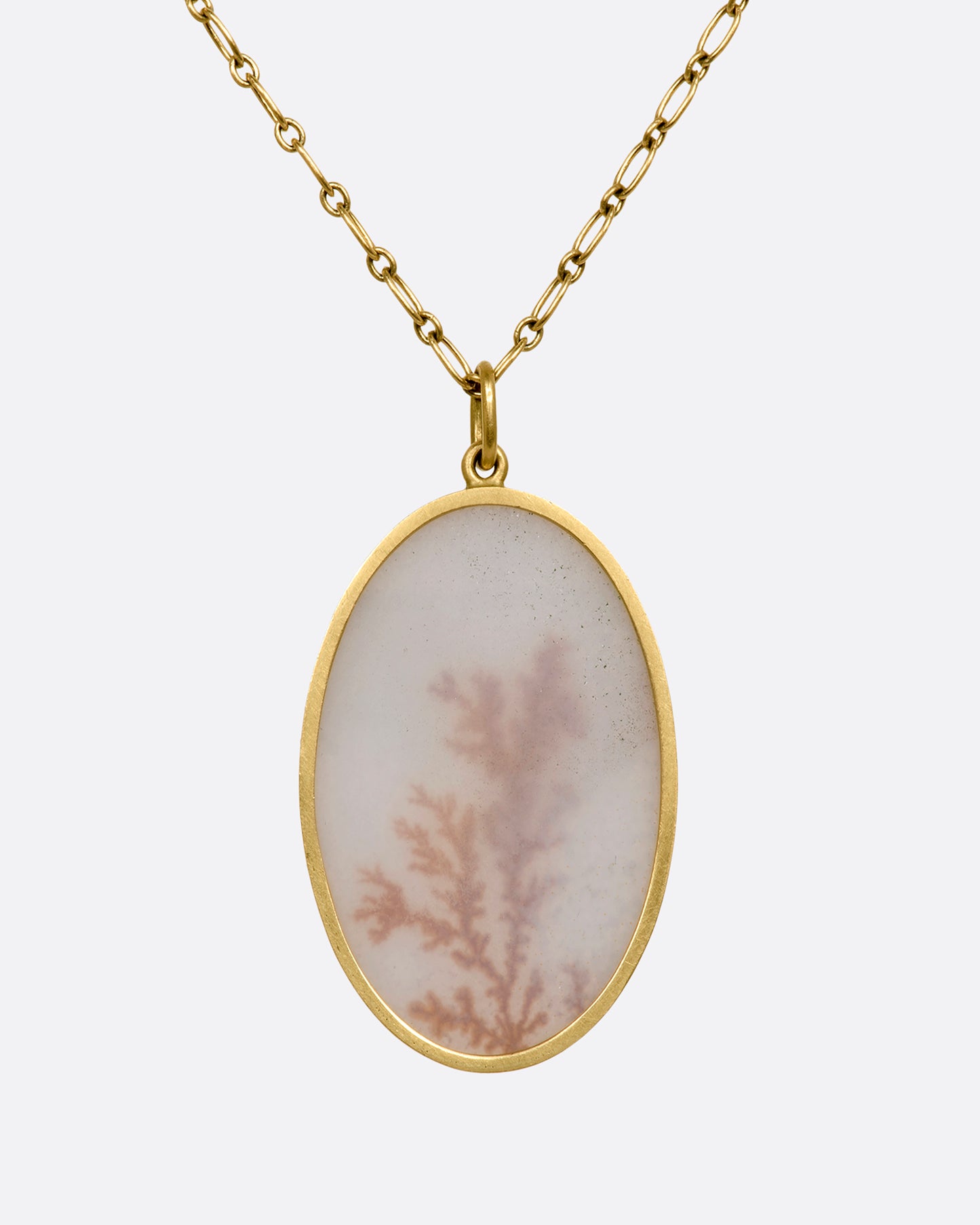 A yellow gold necklace with oval dendritic agate pendant on a yellow gold chain. View up close from the back.