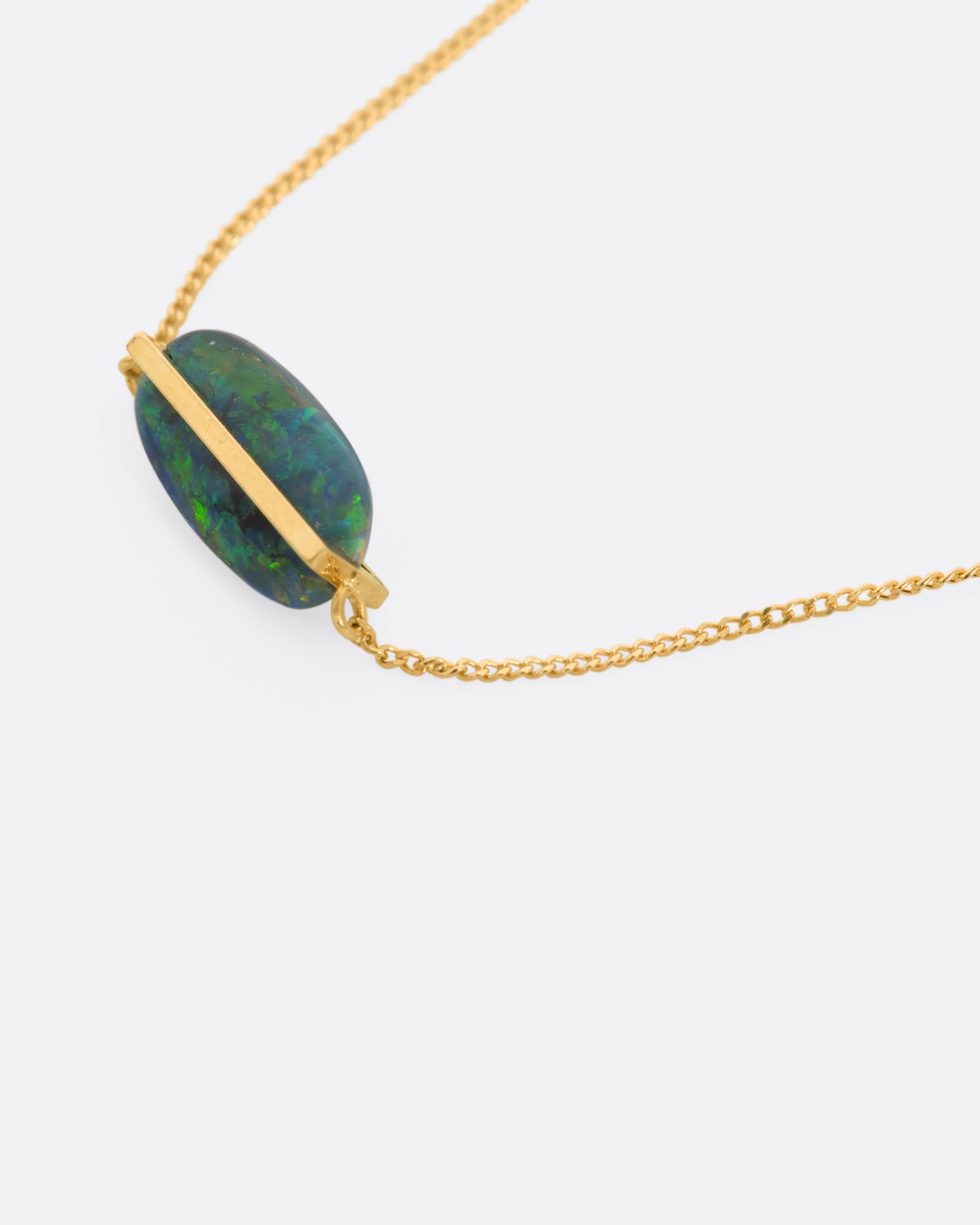 A yellow gold necklace with an oval black opal. View up close from the side.