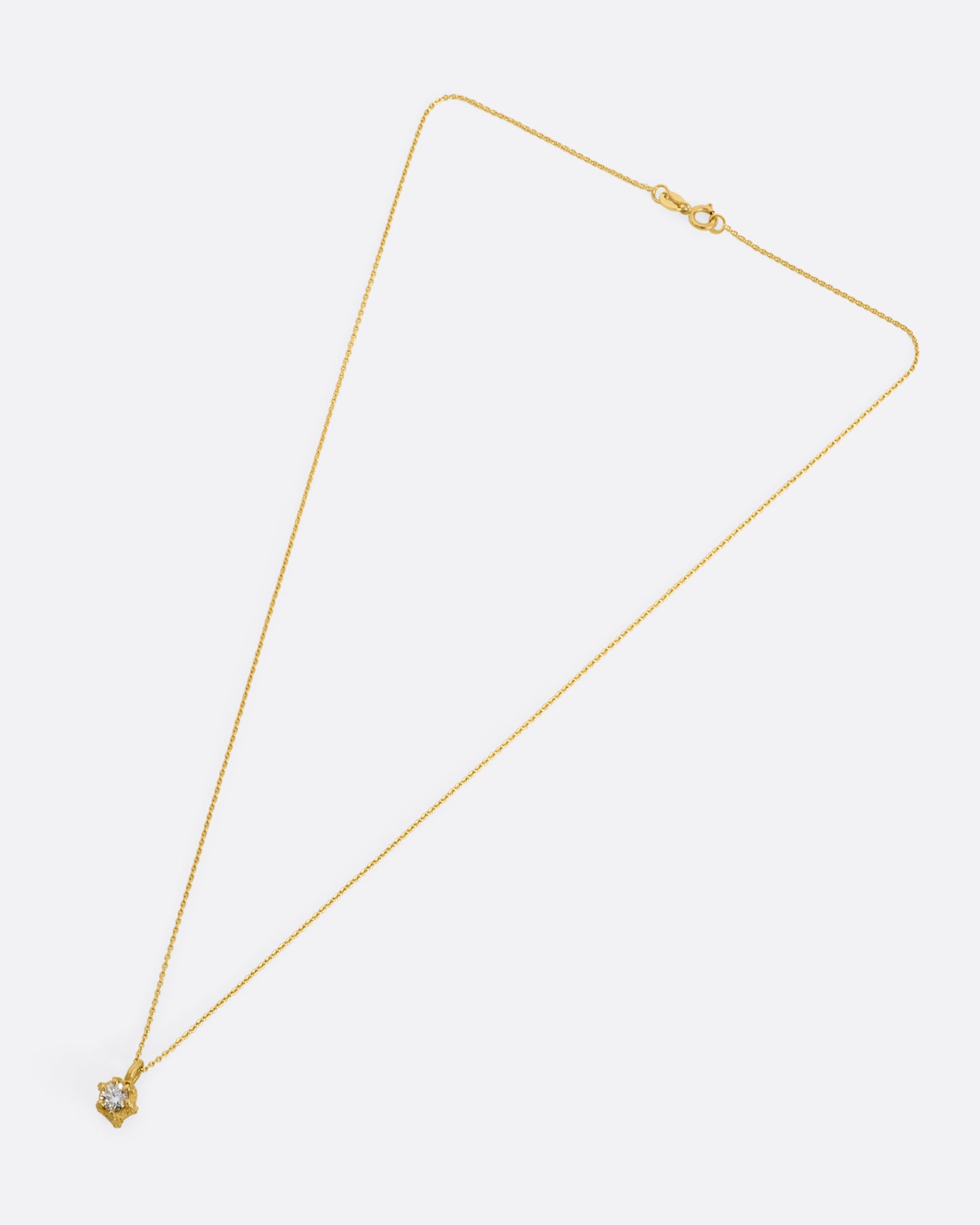 Yellow gold necklace with solitaire diamond in a textured prong setting. View of the entire necklace from above.