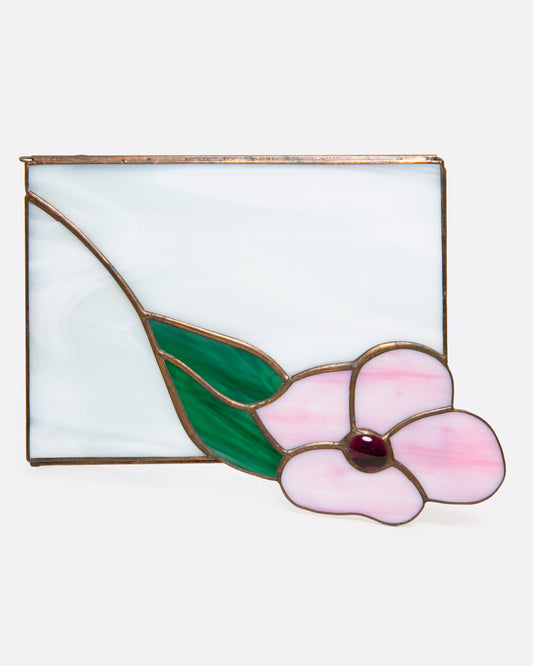 A stained glass box with a pink flower and green leaf, shown from the top.