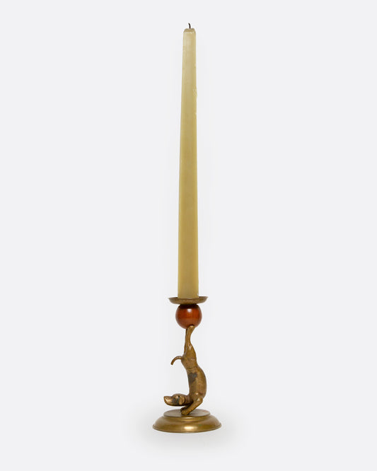 A brass and wooden dog candlestick holder shown from the side.