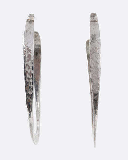A pair of oval silver hammered hoop earrings, shown from the front.
