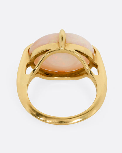 A yellow gold ring with a prong set opal, shown from the back.