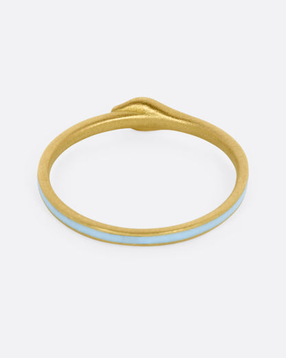 A yellow gold ouroboros ring with diamond eyes and light blue enamel, shown from the back.