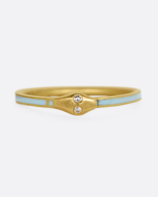 A yellow gold ouroboros ring with diamond eyes and pale blue enamel, shown from the front.  