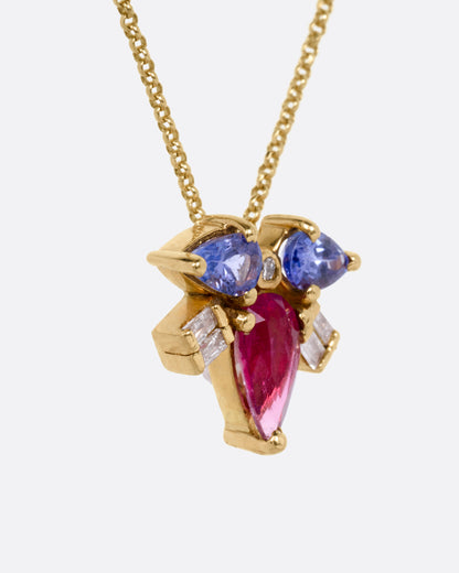 A yellow gold necklace with a muska fly pendant with a pink tourmaline thorax and blue tourmaline and diamond wings, shown from the side.