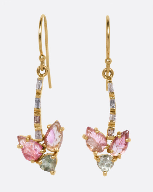 A pair of yellow gold dangle earrings with baguette diamond stems and pink and green tourmalines, shown from the front.