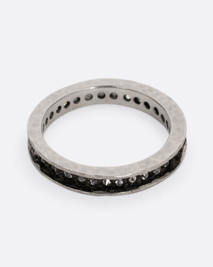 A palladium ring with a queue of diamonds set in a darkened center channel. Shown from the front.