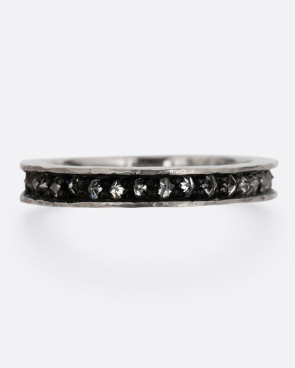 A palladium ring with a queue of diamonds set in a darkened center channel. Shown from the front.
