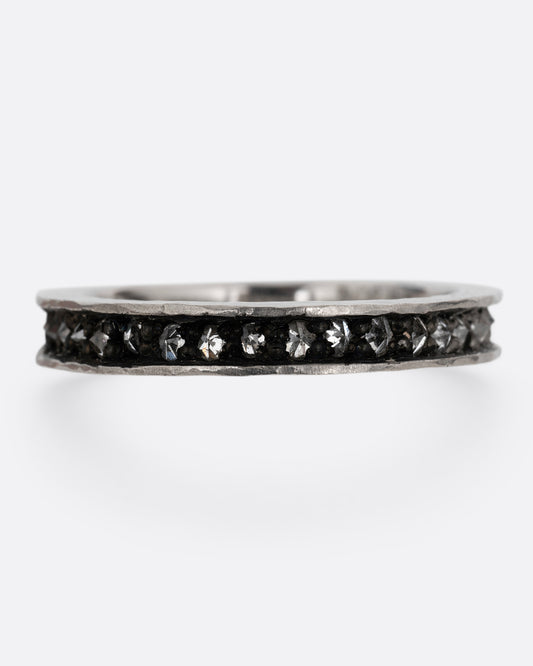 A palladium ring with a queue of diamonds set in a darkened center channel. Shown from the front.