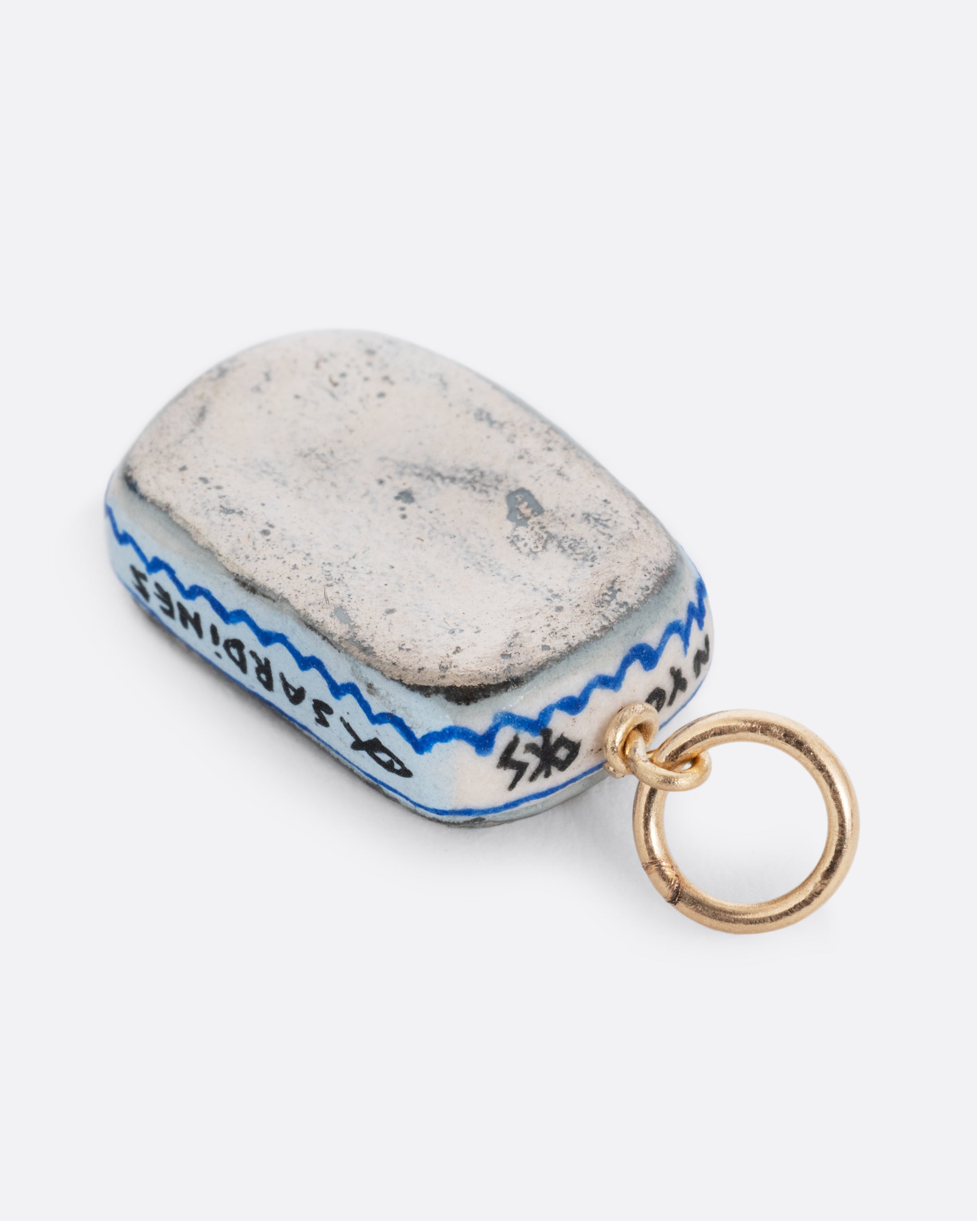 A porcelain hand painted sardine can charm. Shown from the back.