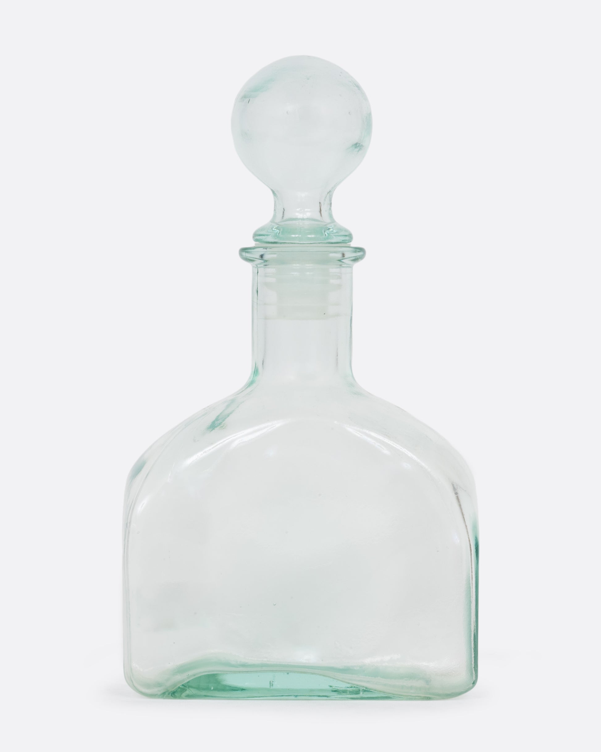 A clear glass decanter with a sphere shaped top. Shown from the front.