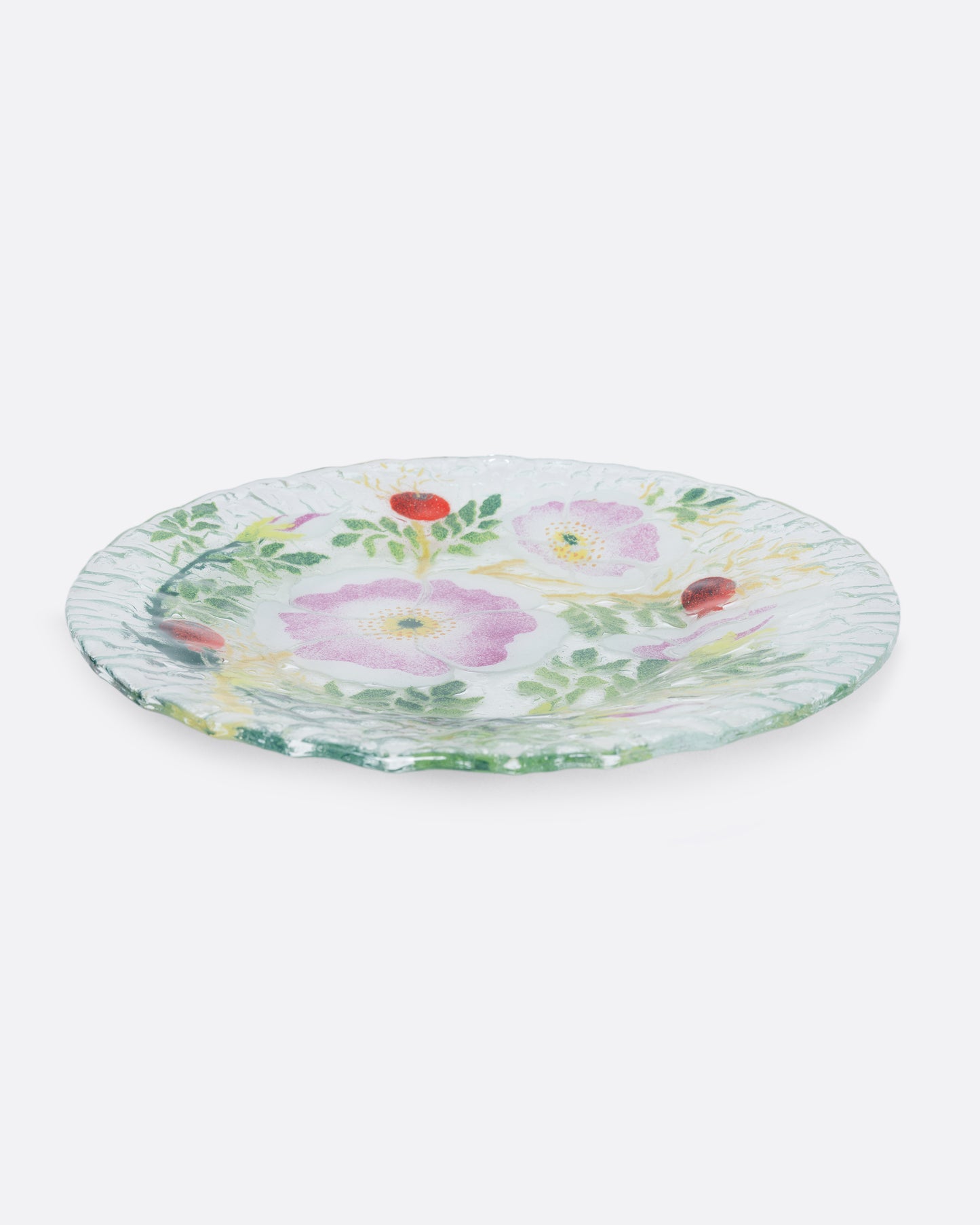 A clear fused glass plate with a floral motif. Shown from the side.