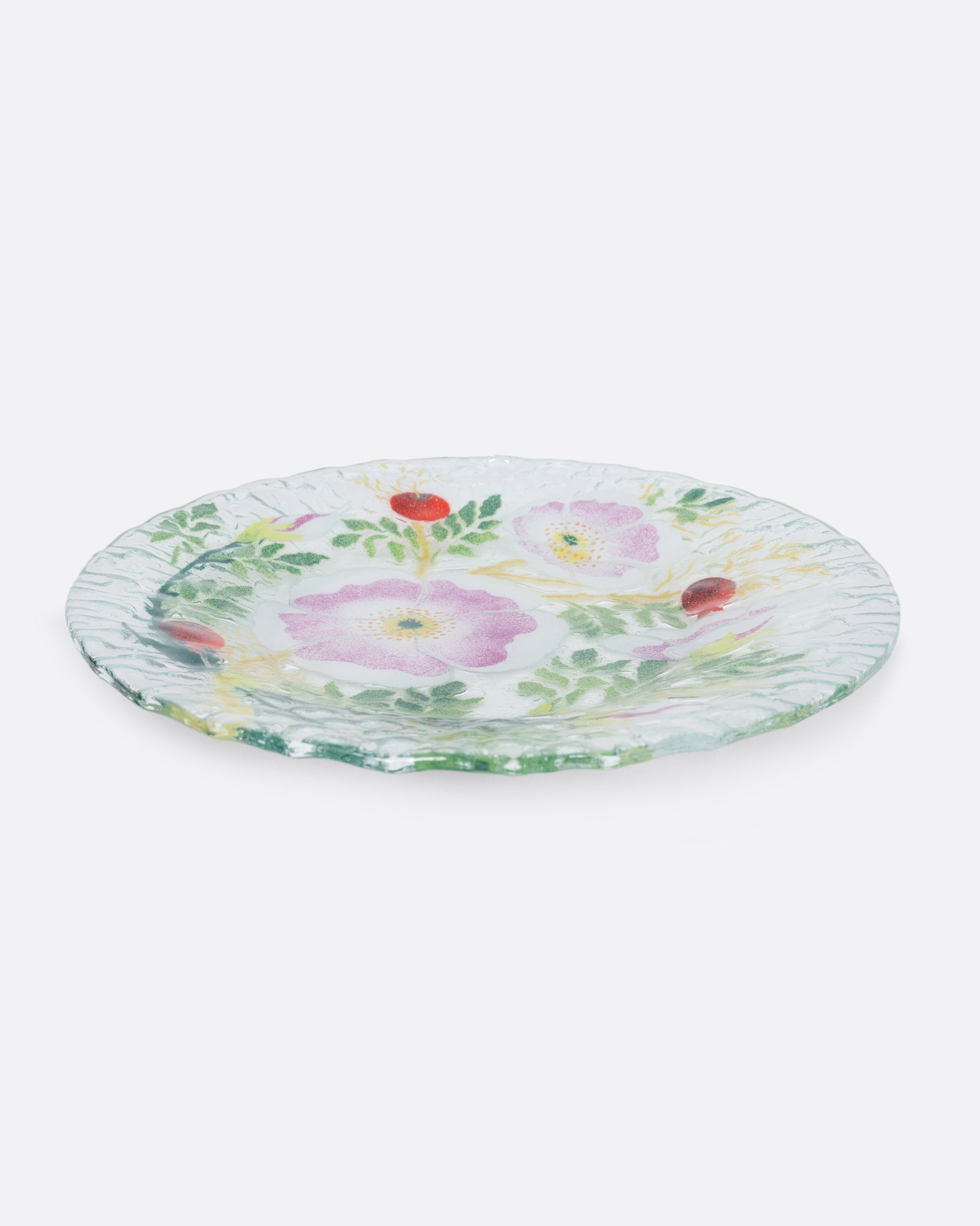 A clear fused glass plate with a floral motif. Shown from the side.