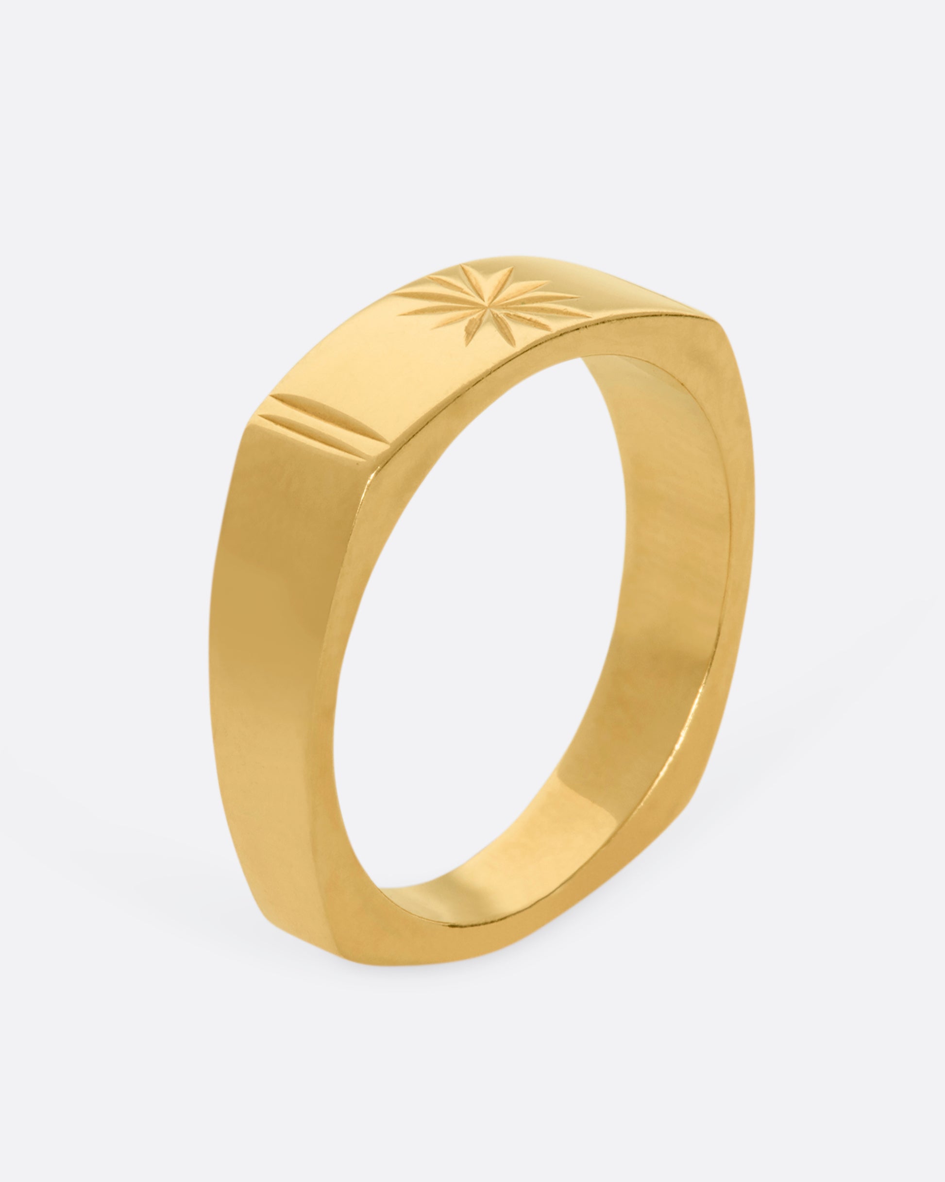 A yellow gold squared band with a star etching on the front. View from the side standing up.