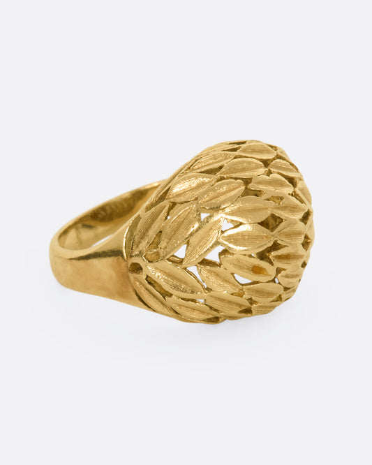 A yellow gold dome shaped ring with a leaf motif. View from the side.