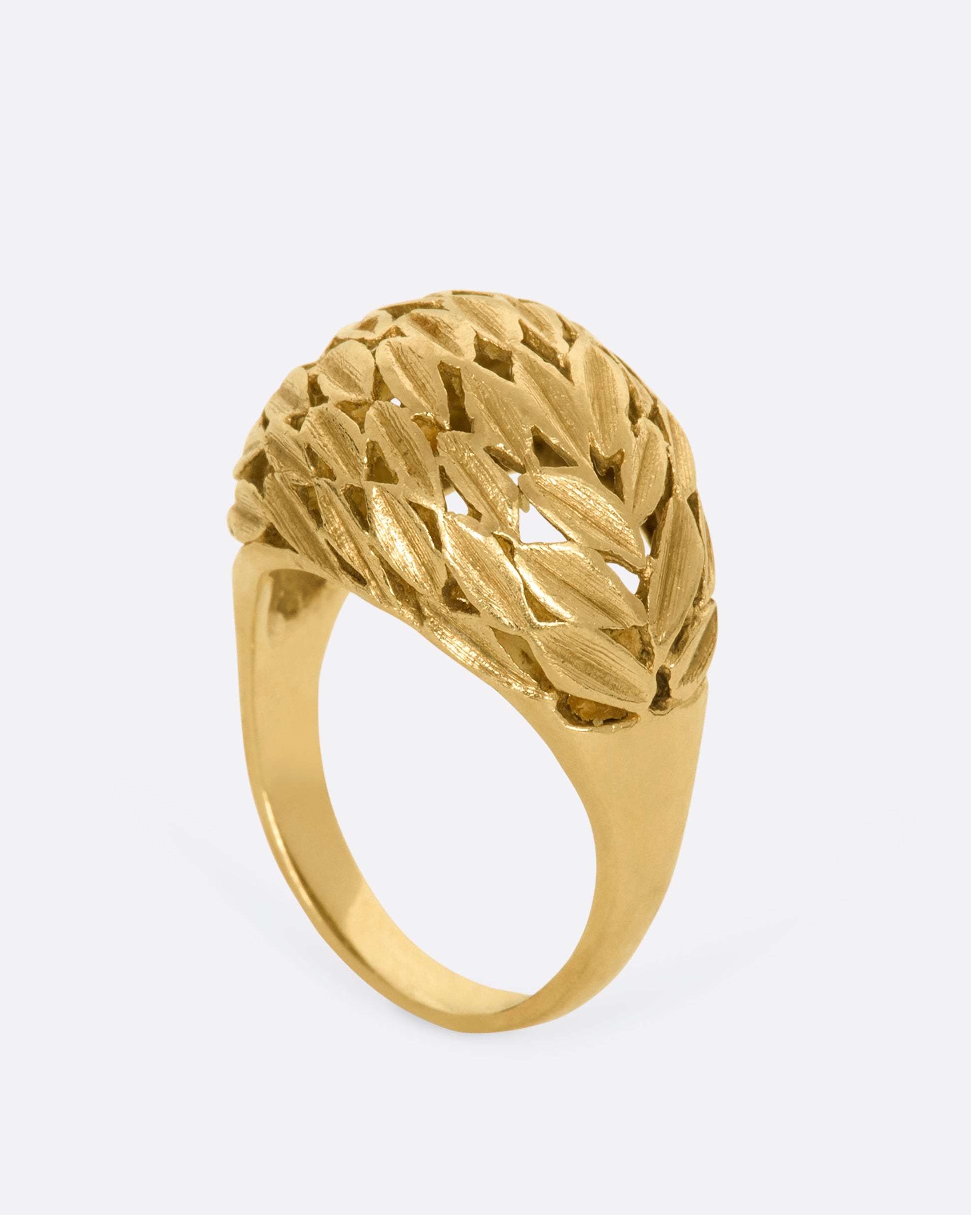 A yellow gold dome shaped ring with a leaf motif. View from the side standing up.