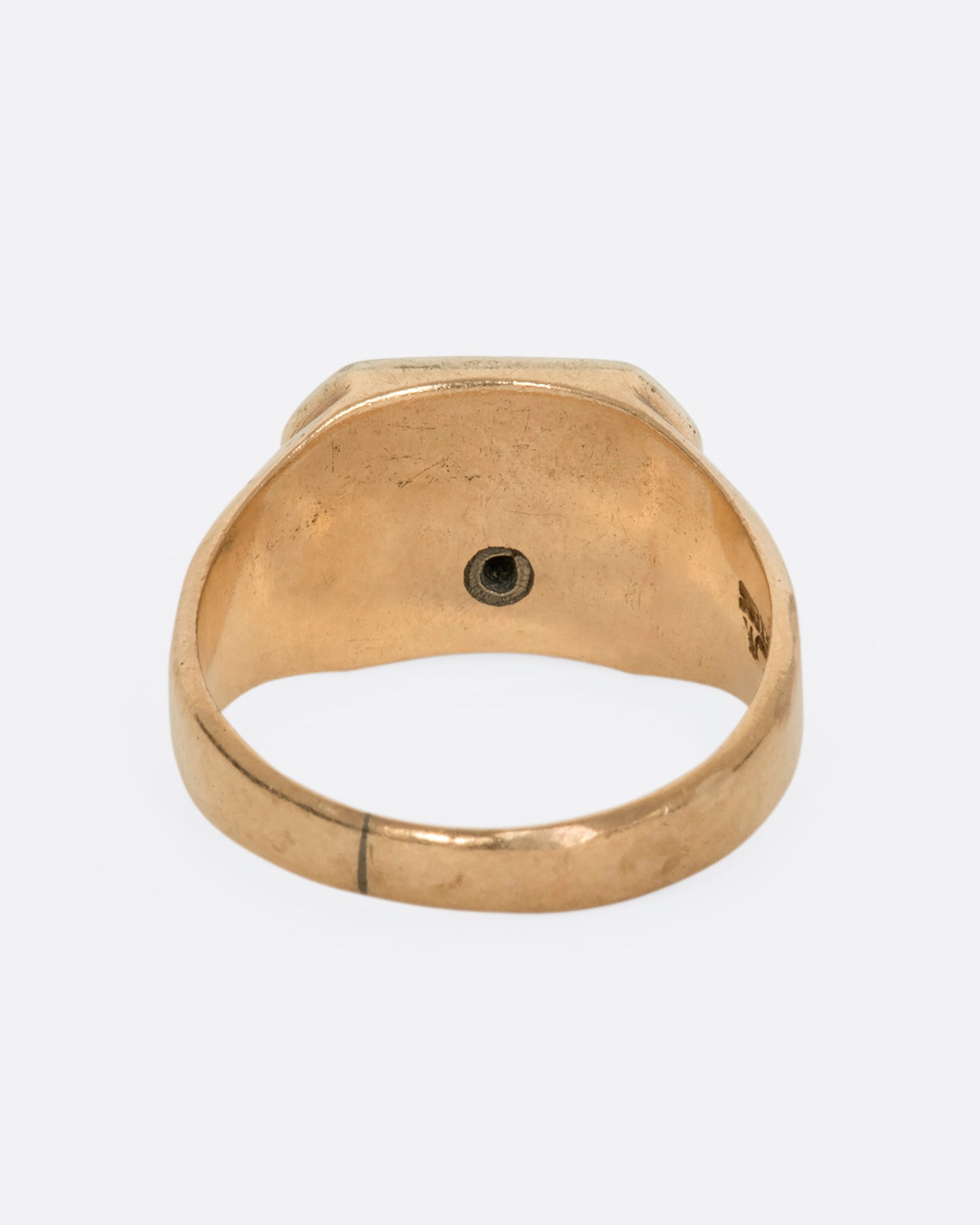 A yellow gold vintage signet ring with an arch and a round diamond on the front and a vase on the shoulder. View from the back.