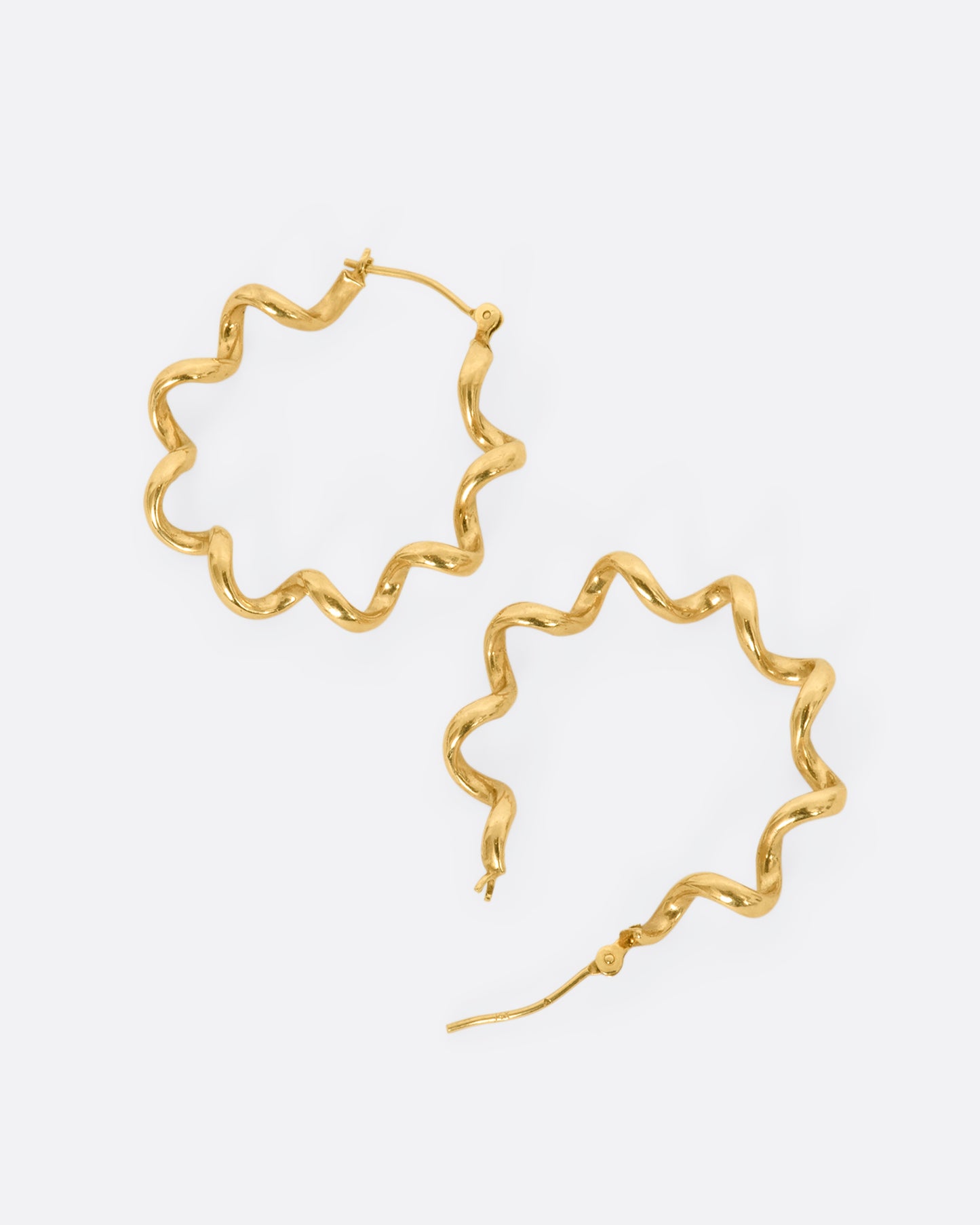 Yellow gold twisted hoop earrings. View laying flat.