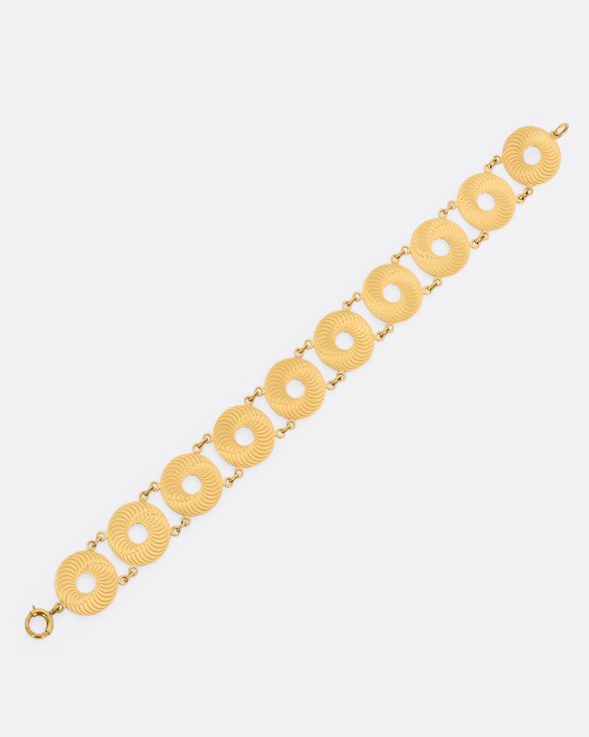 A yellow gold textured disc bracelet. View laying flat.