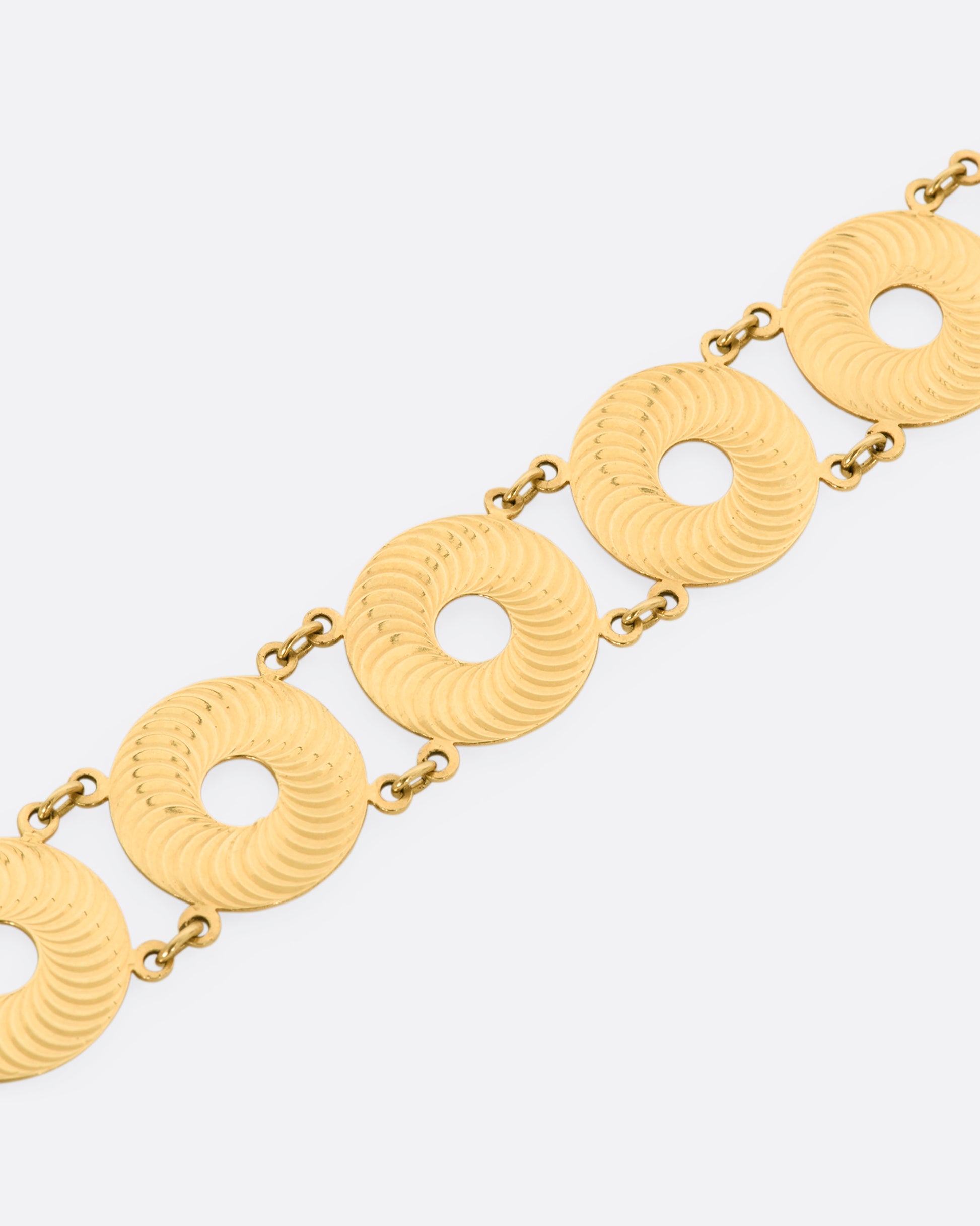 A yellow gold textured disc bracelet. View up close.