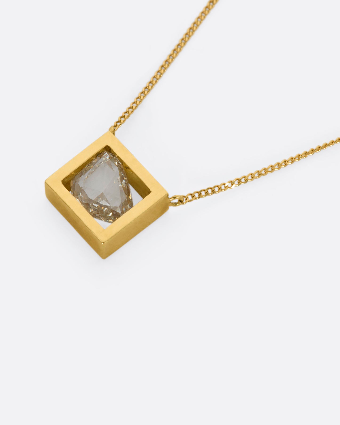 A yellow gold square fixed pendant frame holds a rose cut diamond slice hanging from a chain. View up close laying flat.