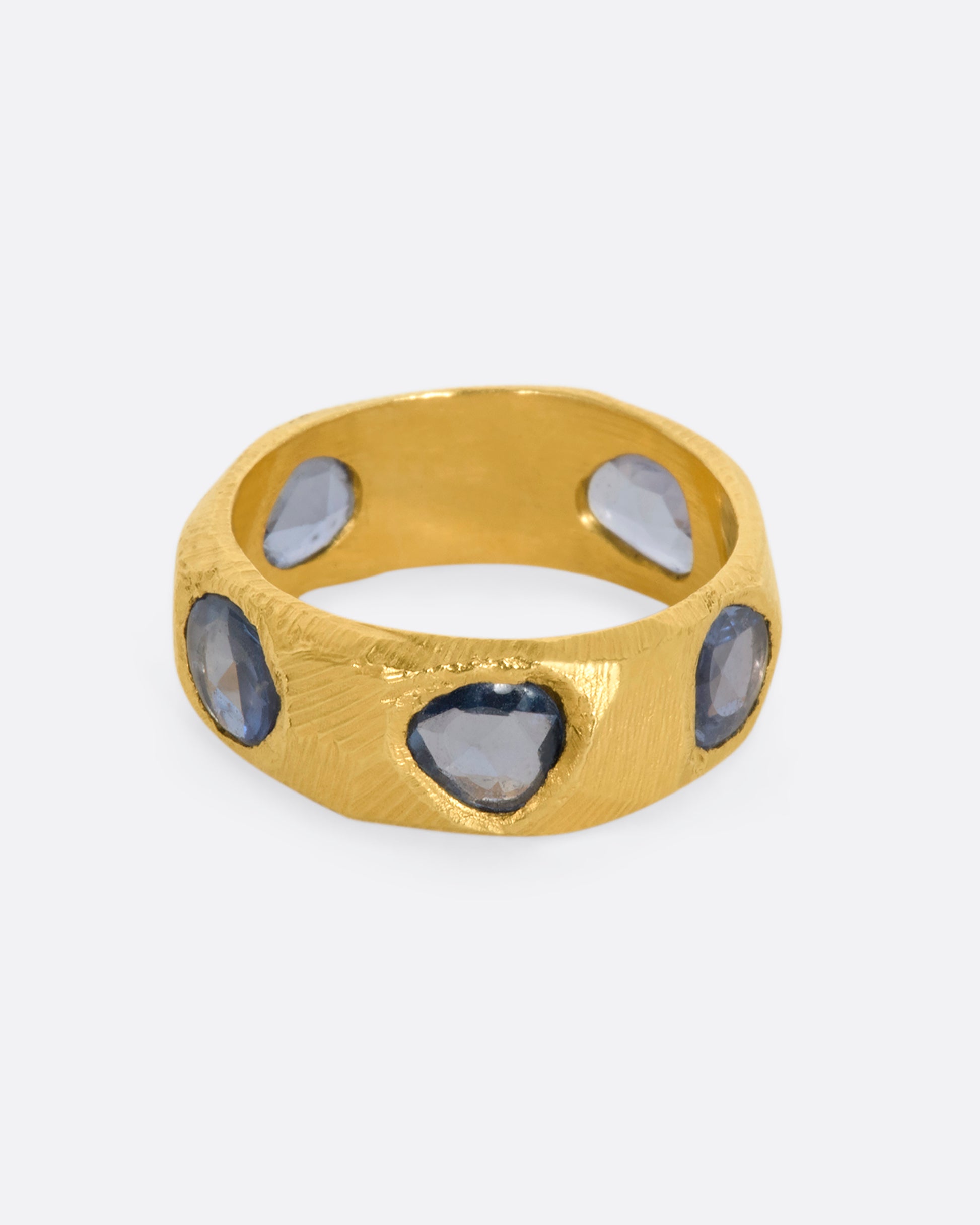 A yellow gold ring with five large blue rose cut sapphires.