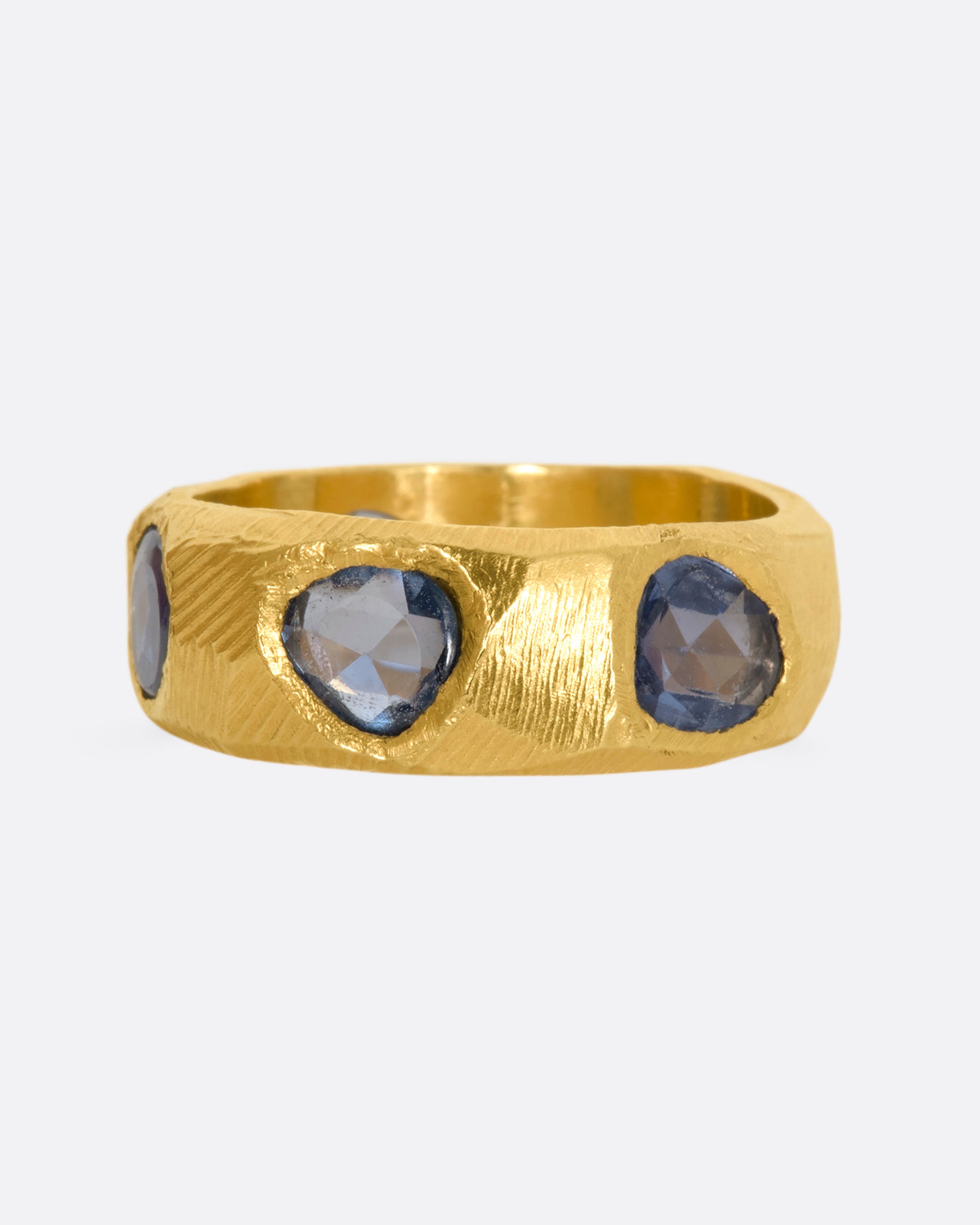 A yellow gold ring with five large blue rose cut sapphires.