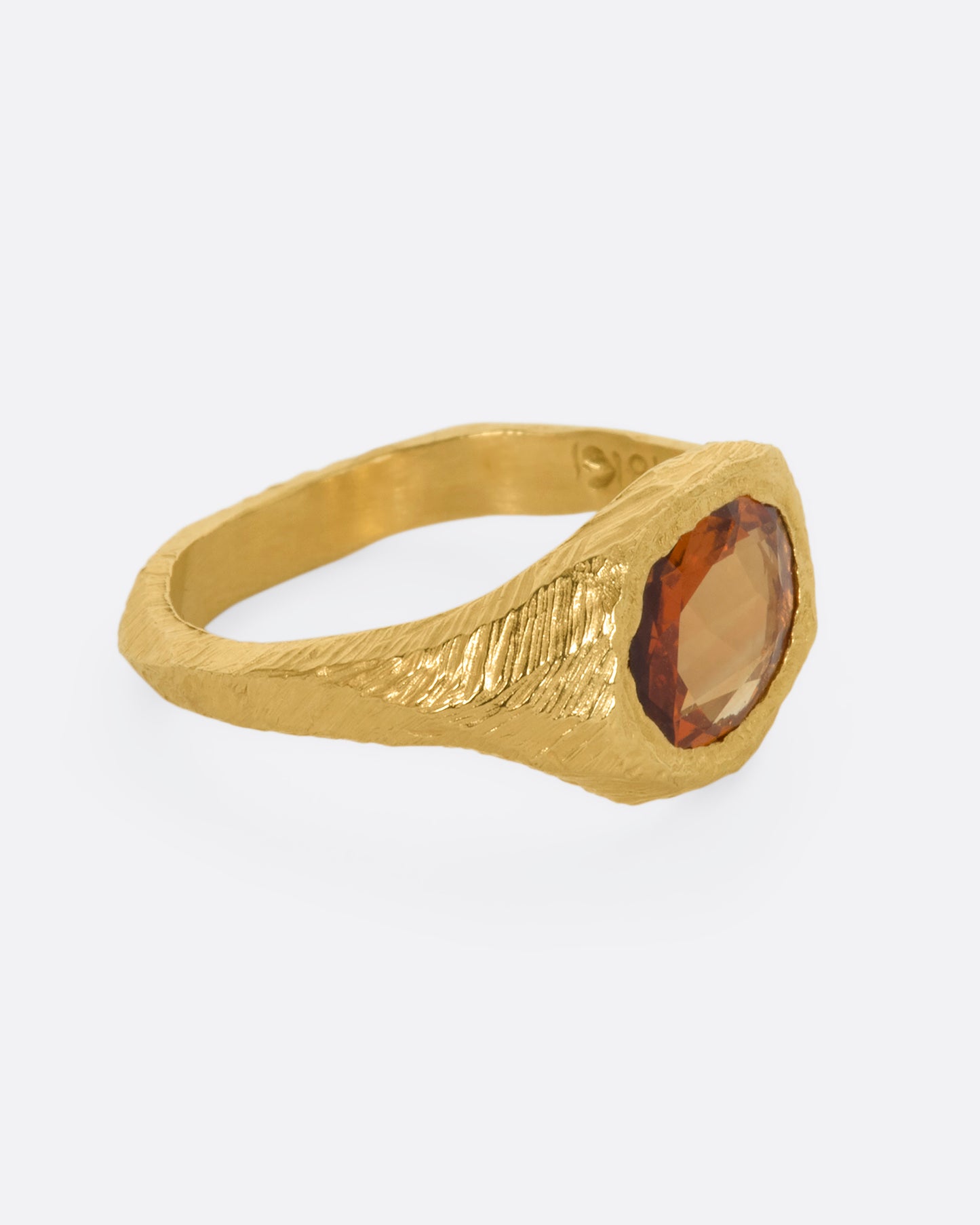 A hand carved yellow gold ring with an orange sapphire. View from the alternate side.