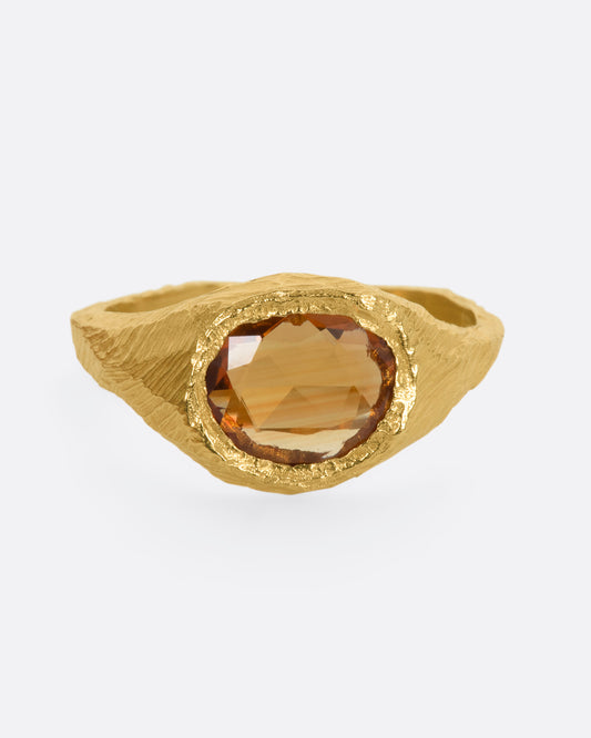 A hand carved yellow gold ring with an orange sapphire. View from the front.