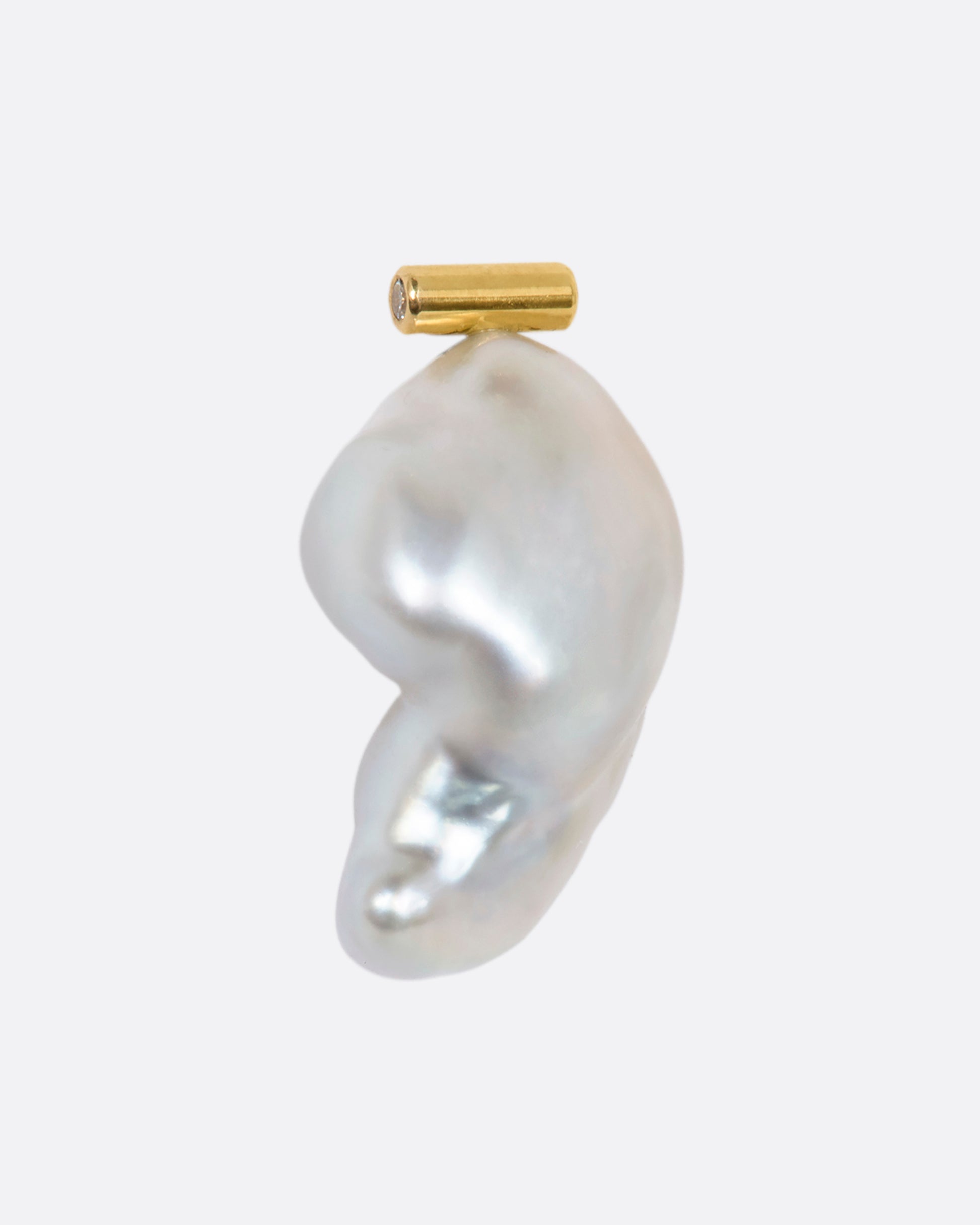 A large baroque pearl stud earring with a yellow gold bar containing diamonds on either end. View from the side.