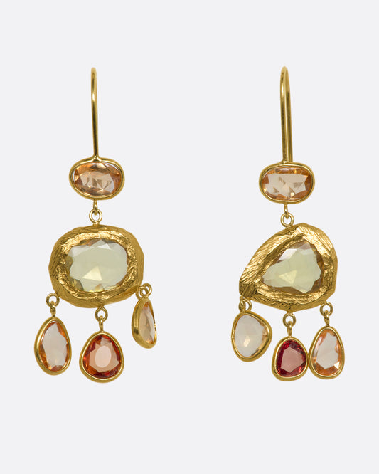 Yellow gold chandelier earrings with three orange sapphires dangling from the bottom. View from the front.