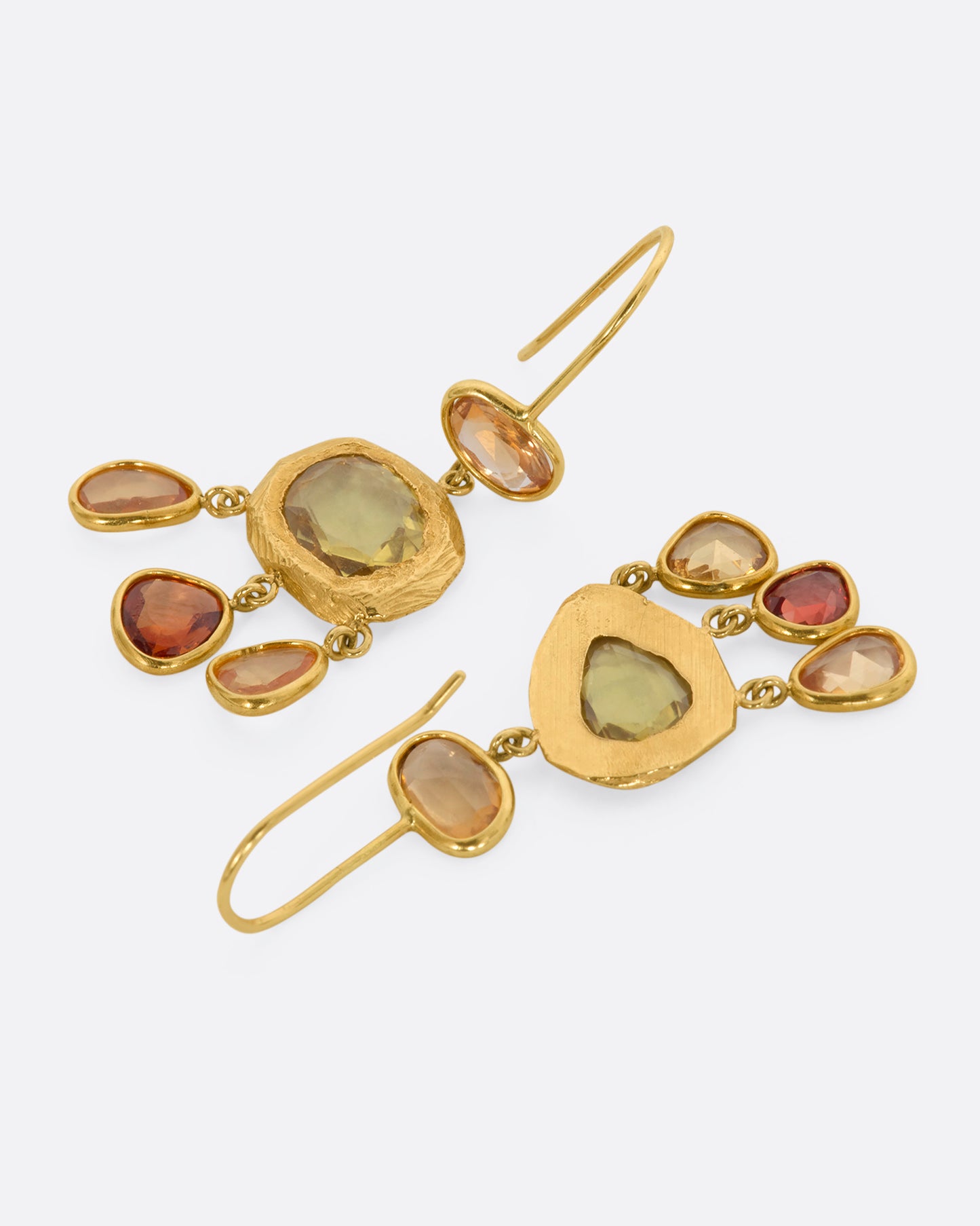 Yellow gold chandelier earrings with three orange sapphires dangling from the bottom. View laying flat.