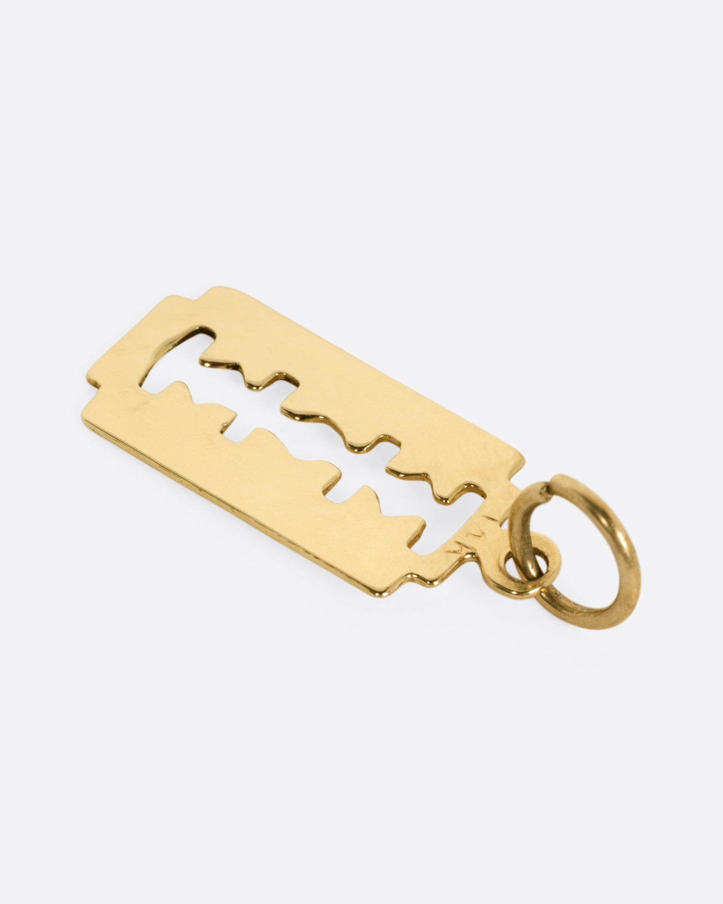 A yellow gold razor blade charm, shown from the back.