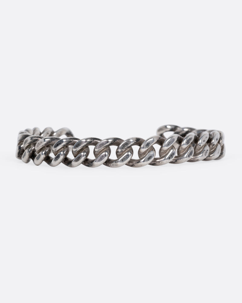 A silver curb chain cuff bracelet shown from the front.