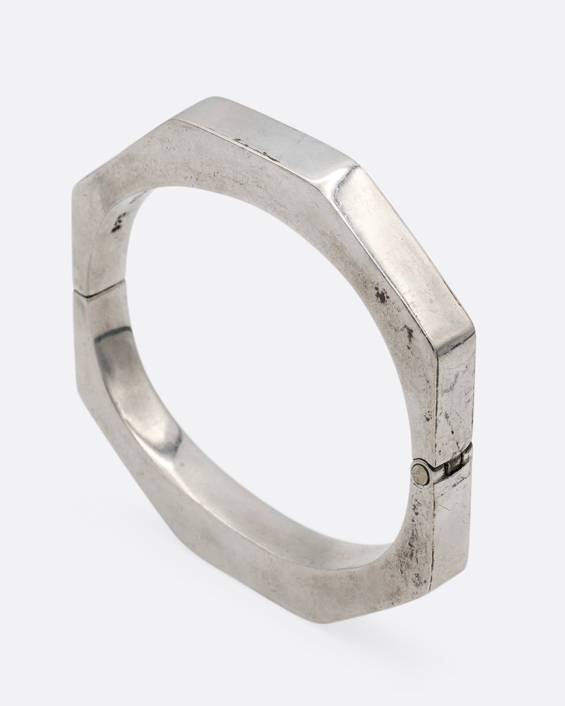 A silver octagonal bangle bracelet, shown standing up from the side.