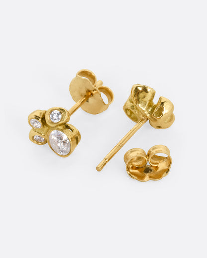 Yellow gold diamond cluster stud earrings, the pair laid flat showing the posts and backs