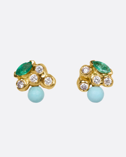 A pair of yellow gold stud earrings with diamonds, emeralds, and turquoise. Shown from the front.