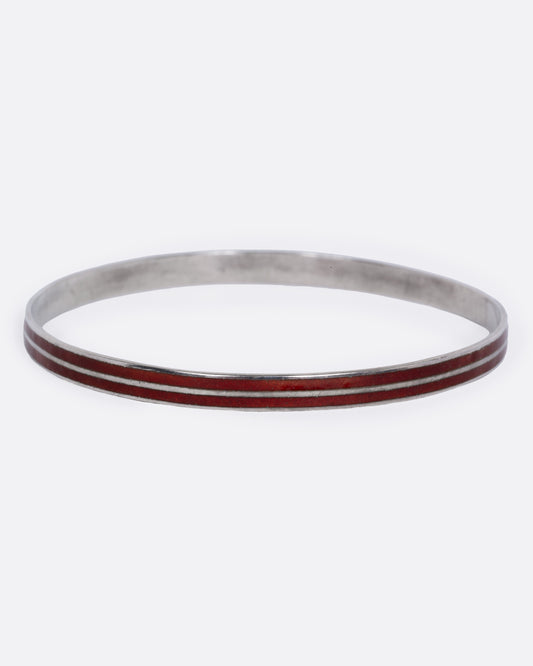 A silver bangle bracelet with two parallel reddish-brown enamel inlay stripes. Shown from the front.