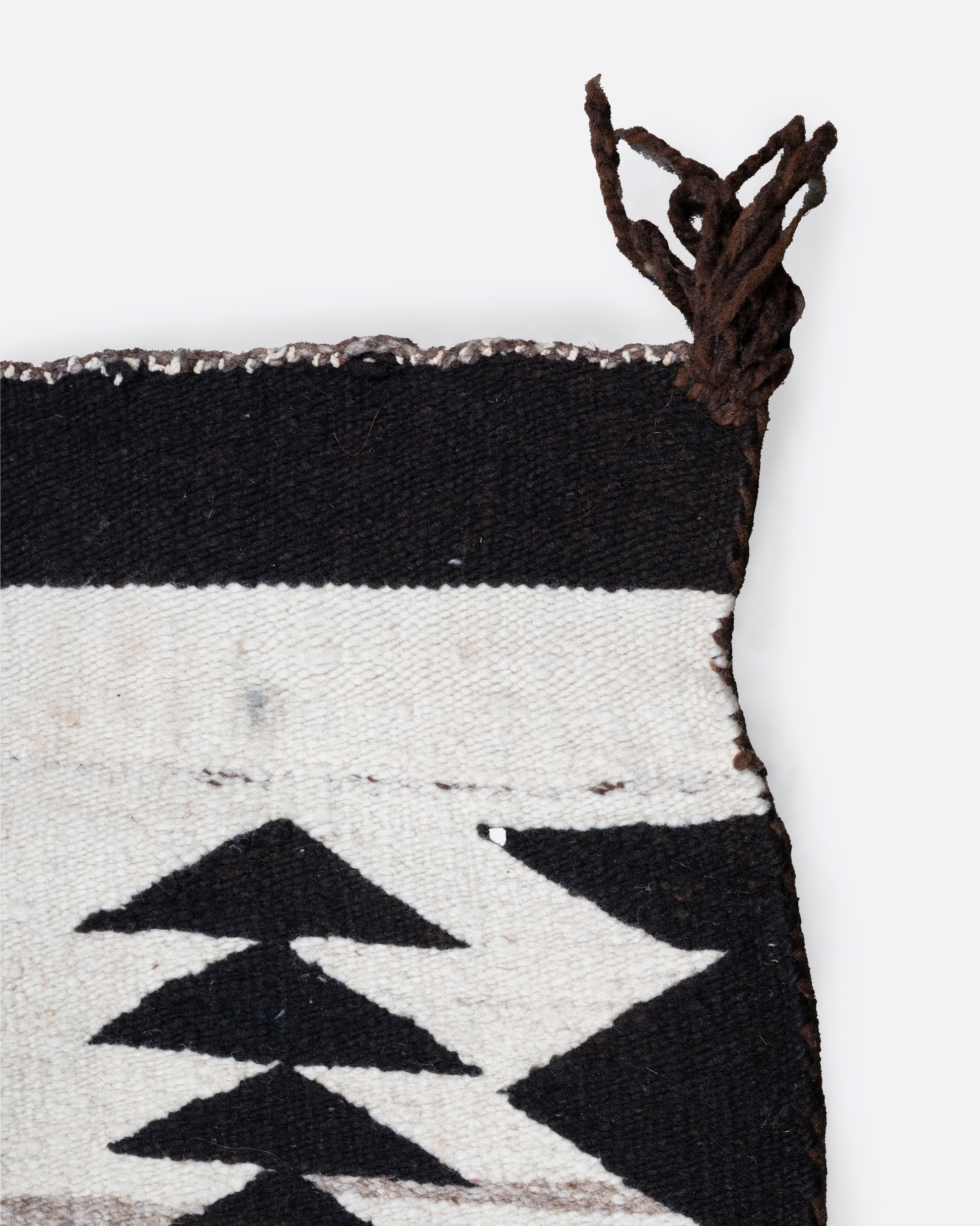 A close up of a white, black, and yellow Navajo Crystal weaving rug with a bold border and stacked diamond pattern.