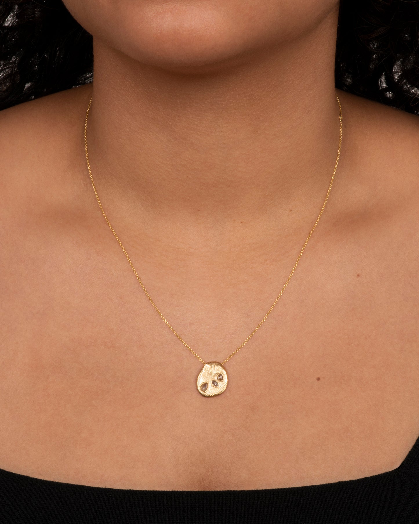 A heavy, hand carved, sliding gold pendant with three rose cut diamonds on a cable chain. View on neck.