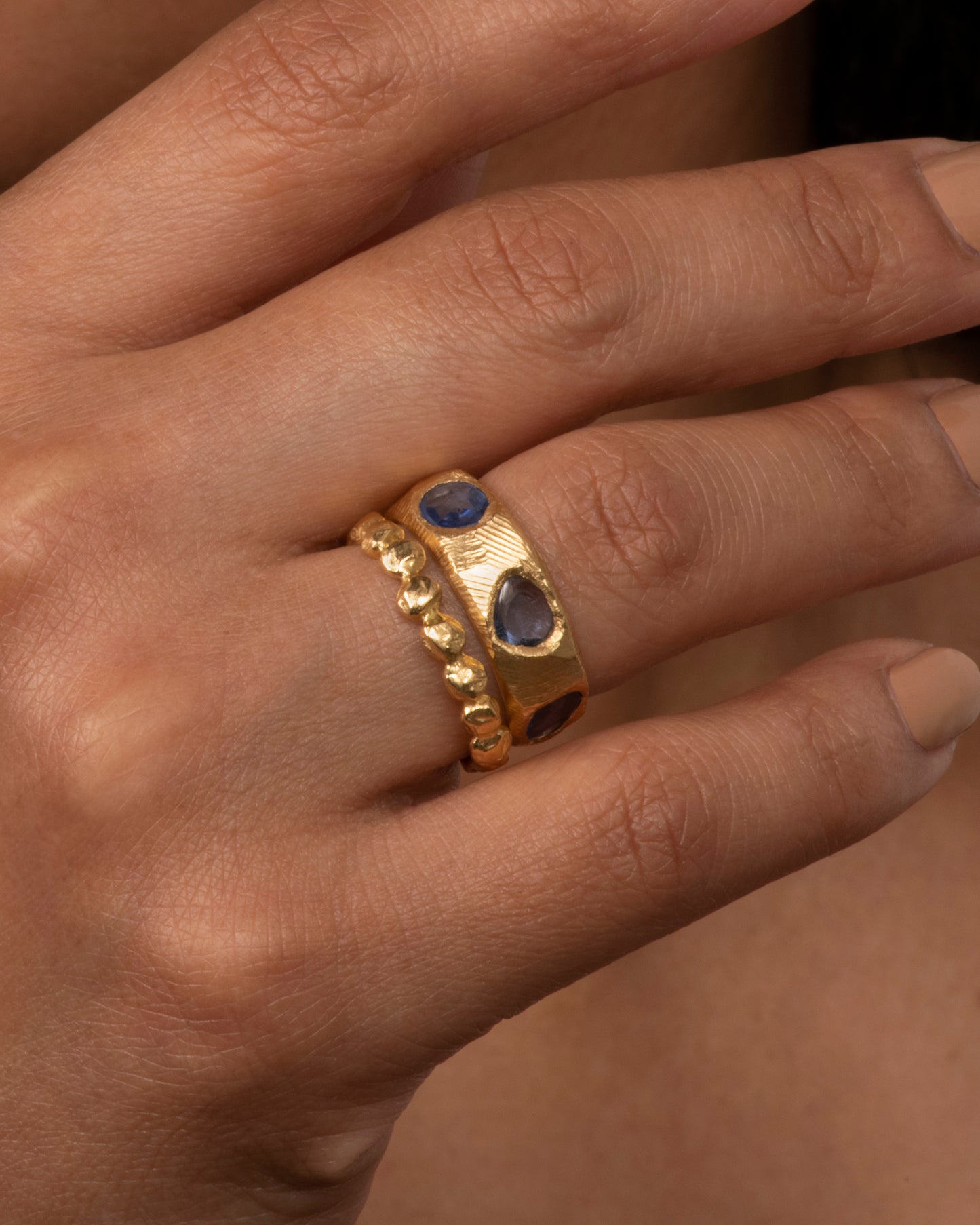 Brushed gold sapphire band with purple sapphires, shown on hand.