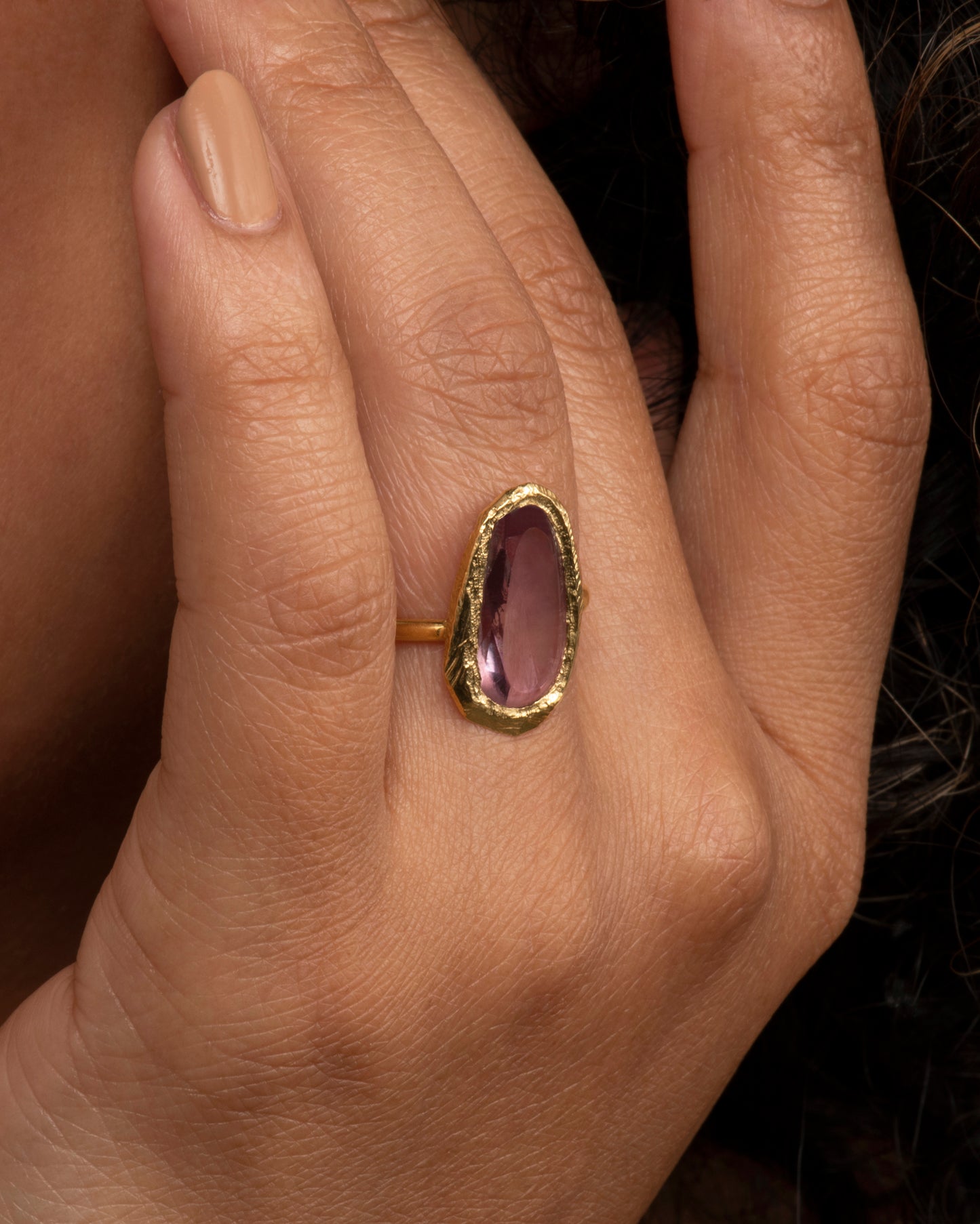 This truly unique freeform, rose-cut purple sapphire is nestled in a hand-carved 18k gold bezel setting. View on a hand.