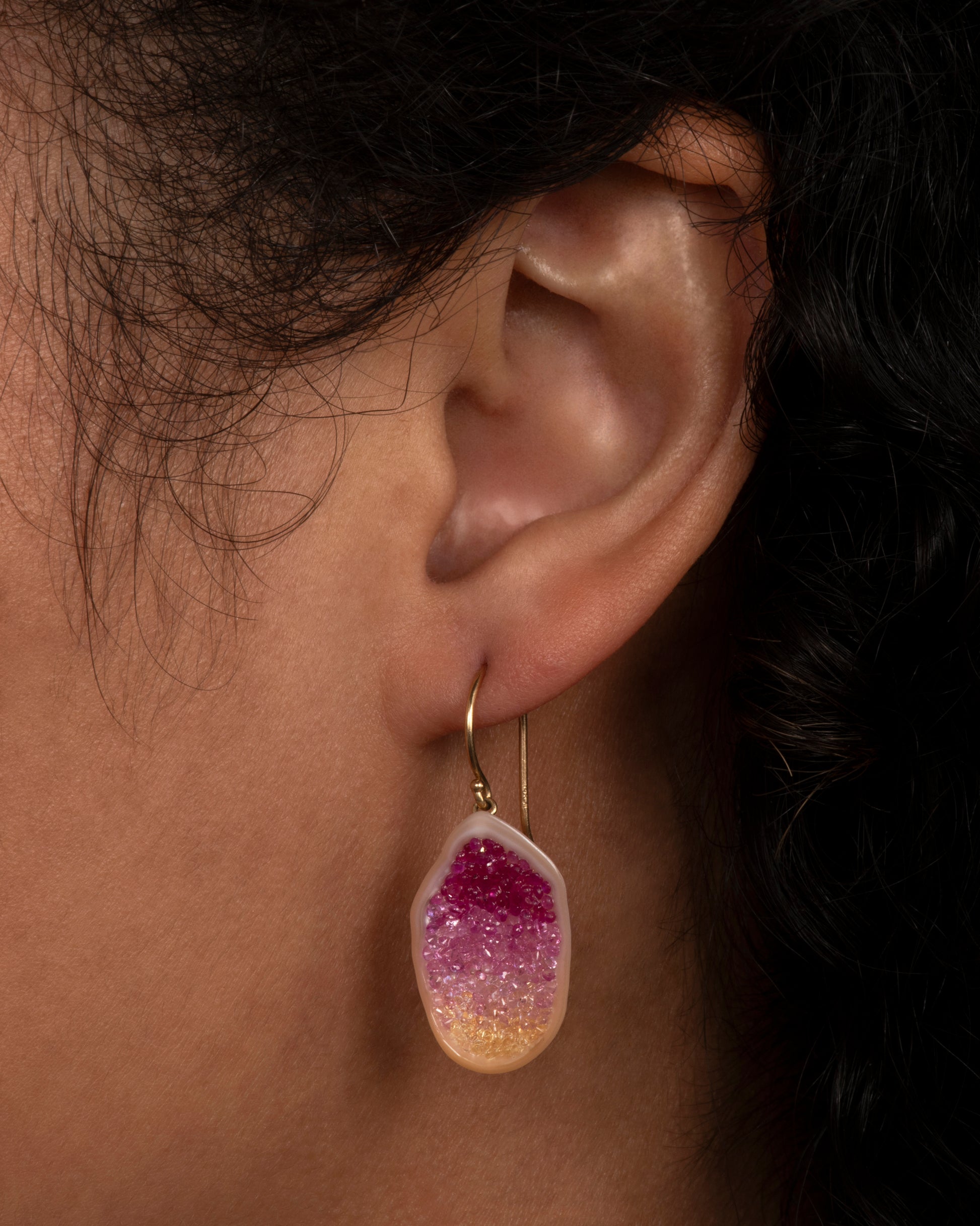 The smooth, soft pearls are lined with reclaimed pink and yellow ombre sapphires. Shown on an ear.