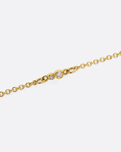 A close up of a diamond accented yellow gold cable chain.