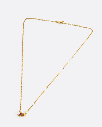 A yellow gold cable chain necklace with a pink sapphire and diamond cluster at the center, shown from the front.