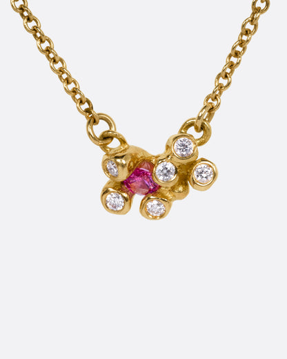 A yellow gold cable chain necklace with a pink sapphire and diamond cluster at the center, shown from the front.